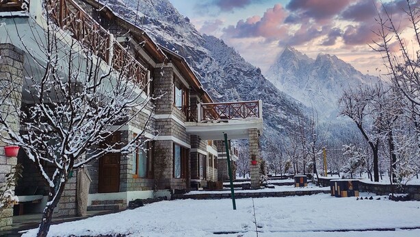 A stone building with a balcony overlooking a snowy mountain landscape. - Banjara Camp and Retreat Sangla (Sangla)