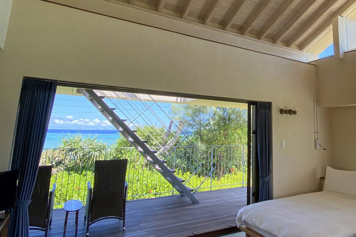 Een slaapkamer met een grote schuifdeur die leidt naar een balkon met uitzicht op de oceaan.