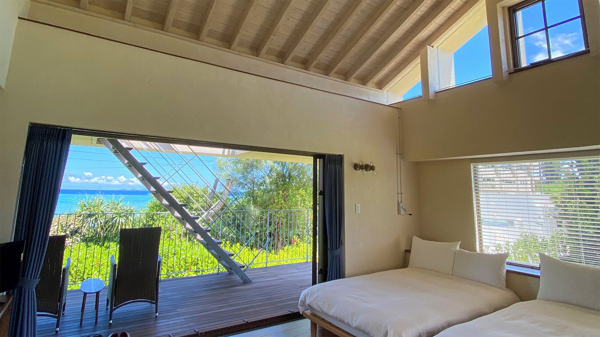 A bedroom with a large window, a bed, and a view of the ocean.