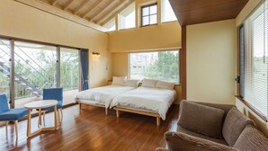 Ein geräumiges Schlafzimmer mit zwei Betten, einer Holzbalkendecke, großen Fenstern und einem Balkon mit Blick.