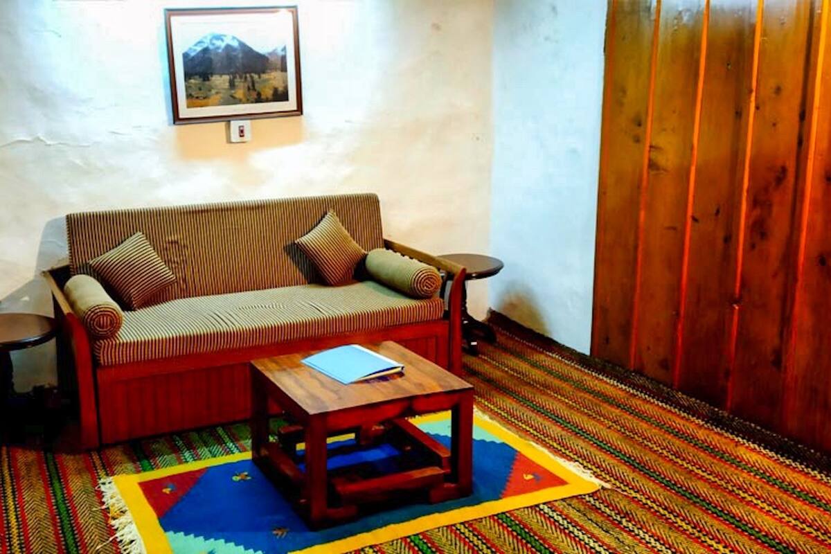 Un salon avec un canapé à rayures, une petite table en bois et un tapis coloré.