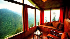Un chalet confortable doté d’une grande fenêtre donnant sur un paysage de montagnes boisées.