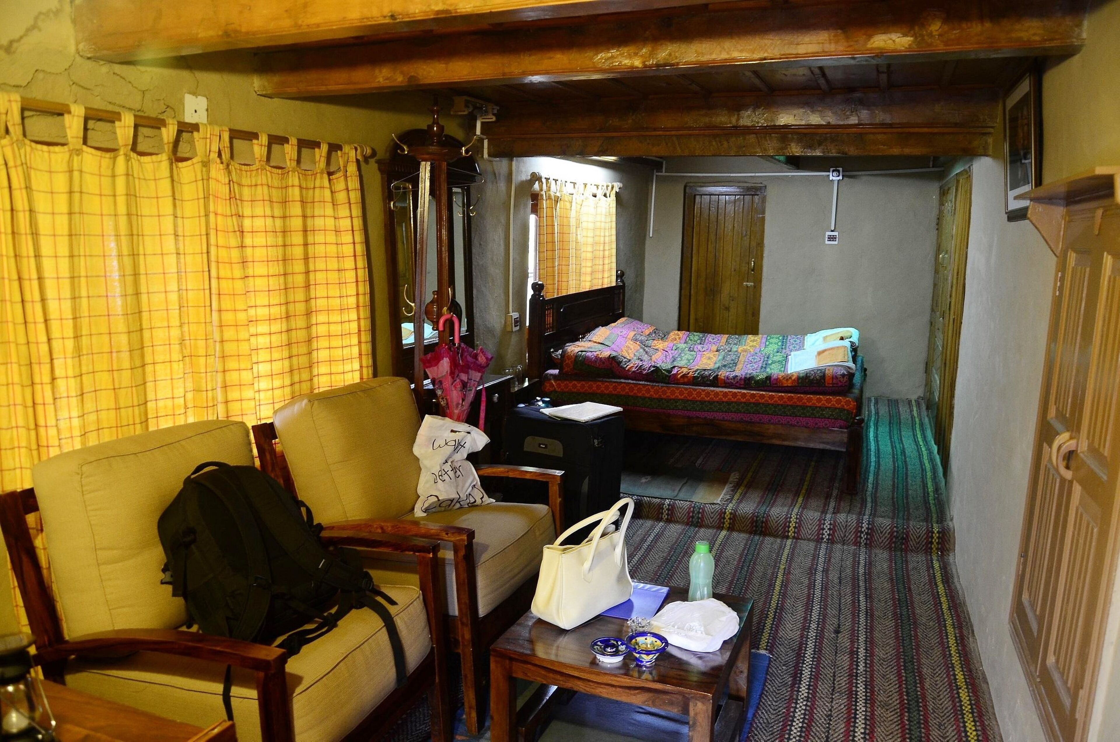 A room with a bed, a chair, a table, and a suitcase.