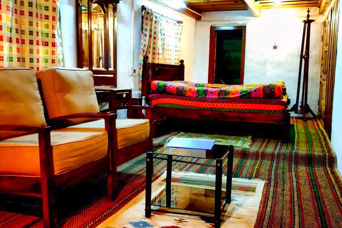 Une pièce comprenant un lit, deux chaises, une petite table et un tapis à motifs.