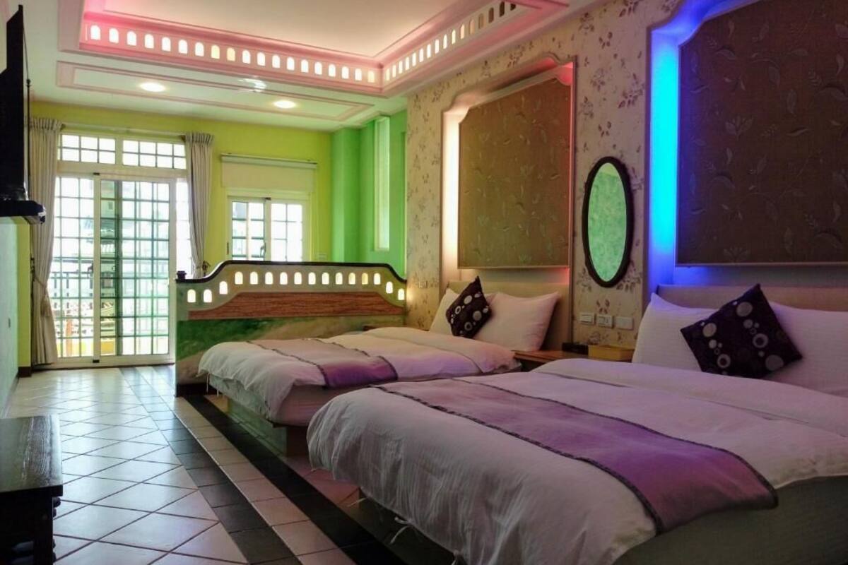 A hotel room with two beds, a staircase, and a view of the outside.