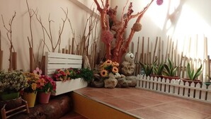 Un área de recepción con un banco de madera, plantas en macetas y una estructura arbórea decorativa.