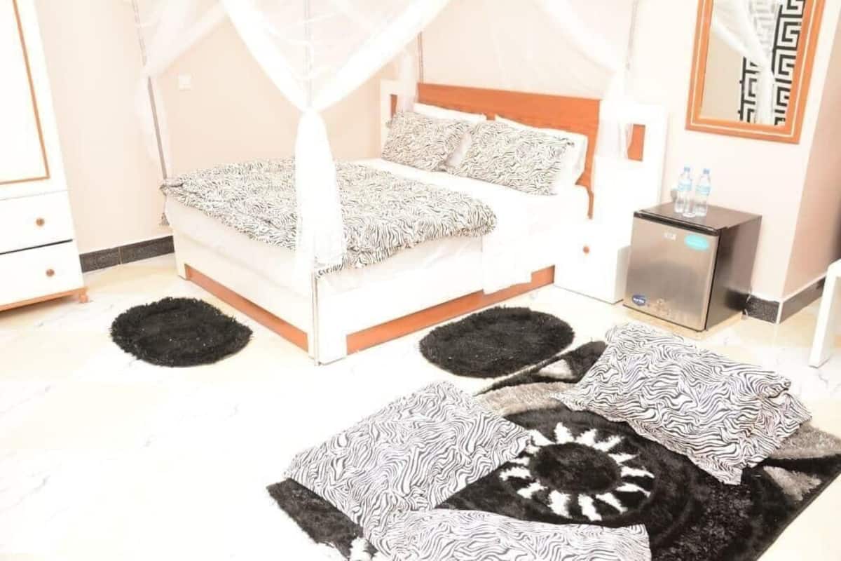 A bedroom with a bed, a bedside table, a water dispenser, and a mirror on the wall.