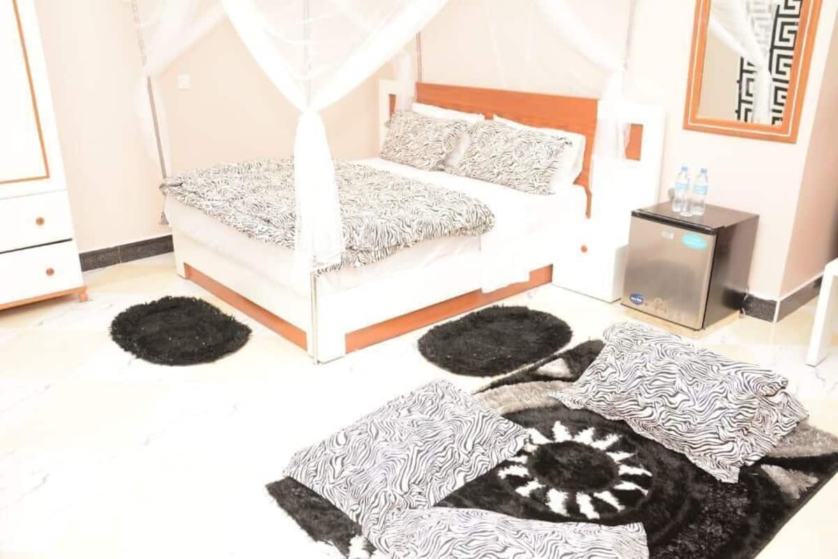 A bed with a canopy, a bedside table with a water bottle, and a small refrigerator.