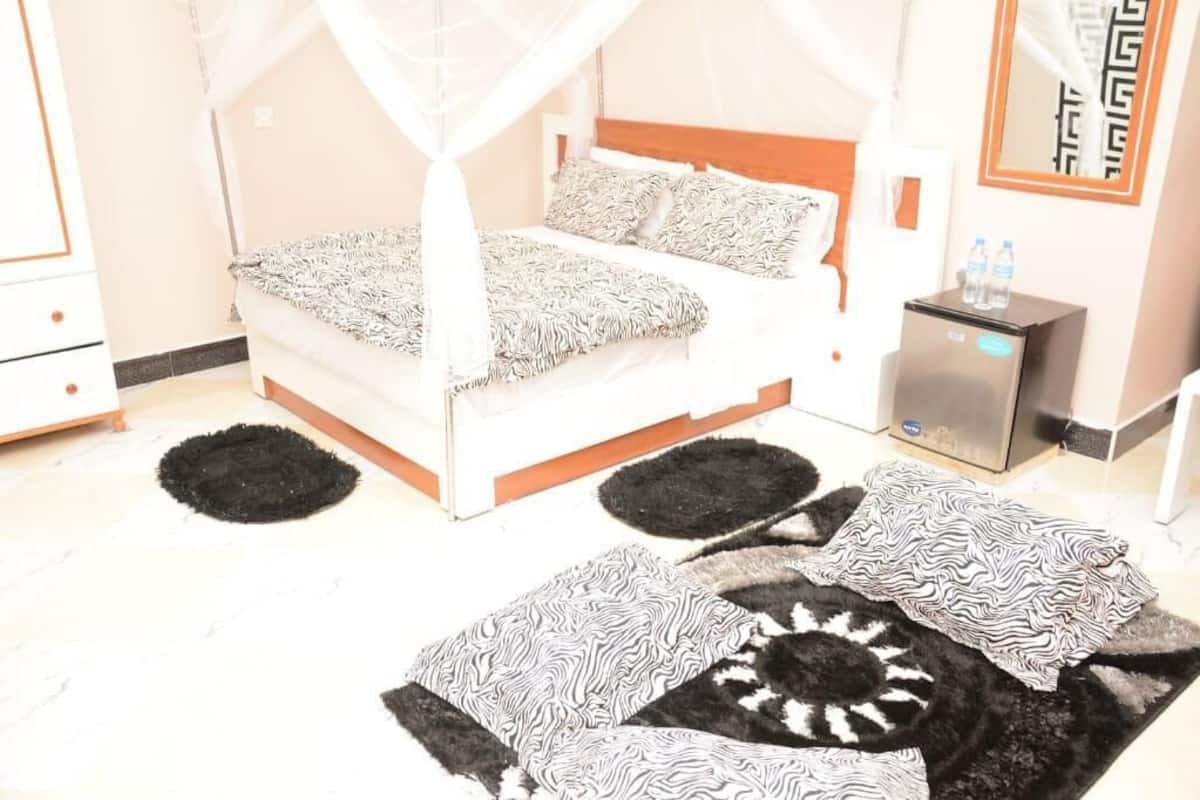 A bedroom with a bed, bedside tables, a refrigerator, and a mirror.