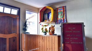 Un área de recepción con un mostrador de madera, un letrero de bienvenida y un pequeño altar con objetos religiosos.