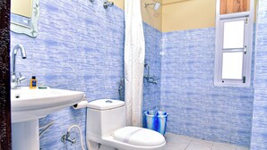 Un baño con inodoro, lavabo, ducha y paredes con un estampado azul.