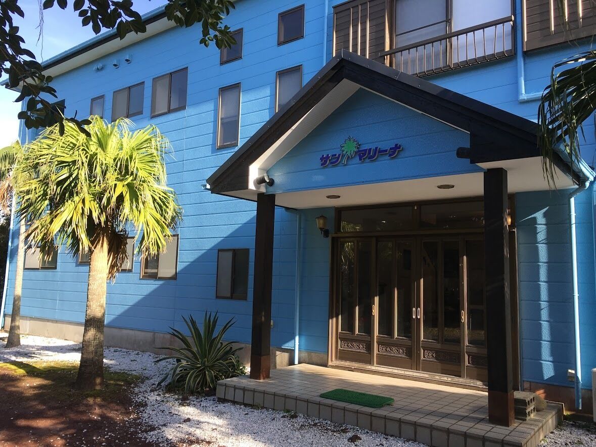A hotel entrance with a blue facade, palm trees, and a sign reading "Sofitel Marina."