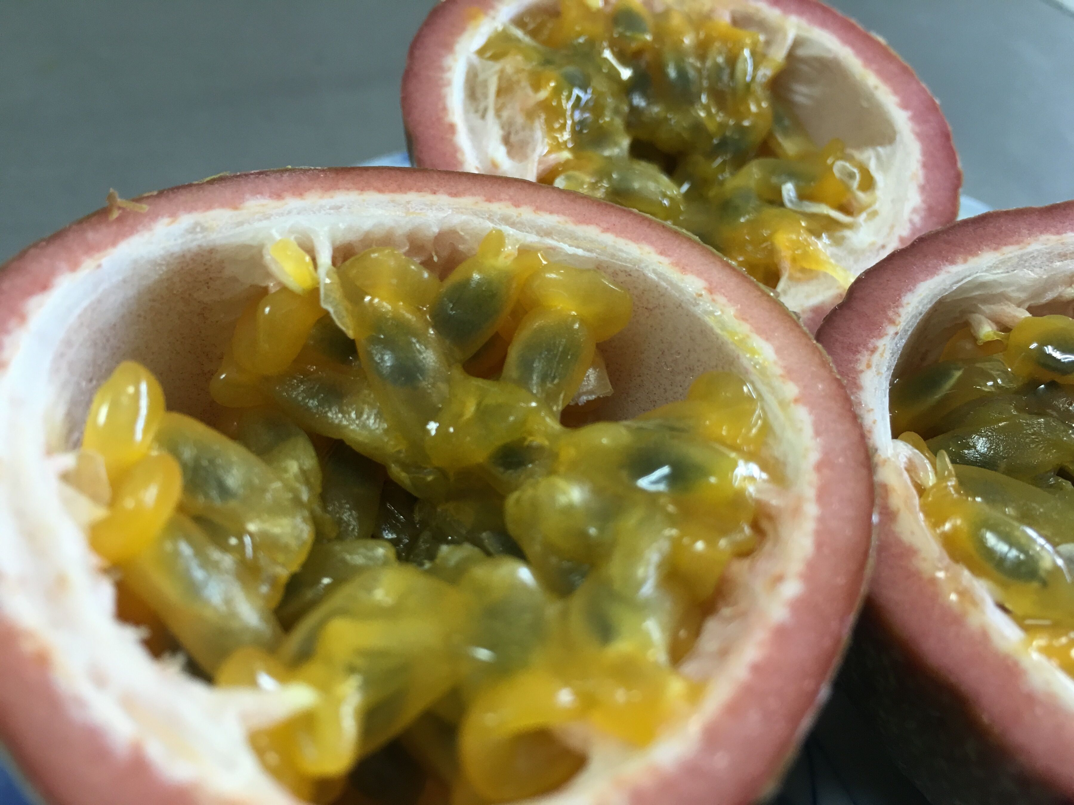 Eine Nahaufnahme von Leidenschaftsfrüchten, halbiert und gefüllt mit gelbem Fruchtfleisch und Kernen.