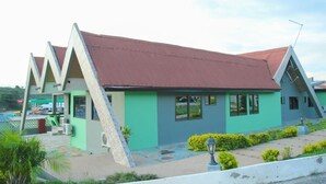 A building with a sloped roof and a green facade. - Mama Lee's Lodge - Yamoransa (Fomena)