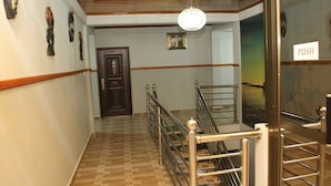 A hallway with a wooden floor, a metal railing, and a 'PUSH' sign on a door. - Mama Lee's Lodge - Yamoransa (Fomena)