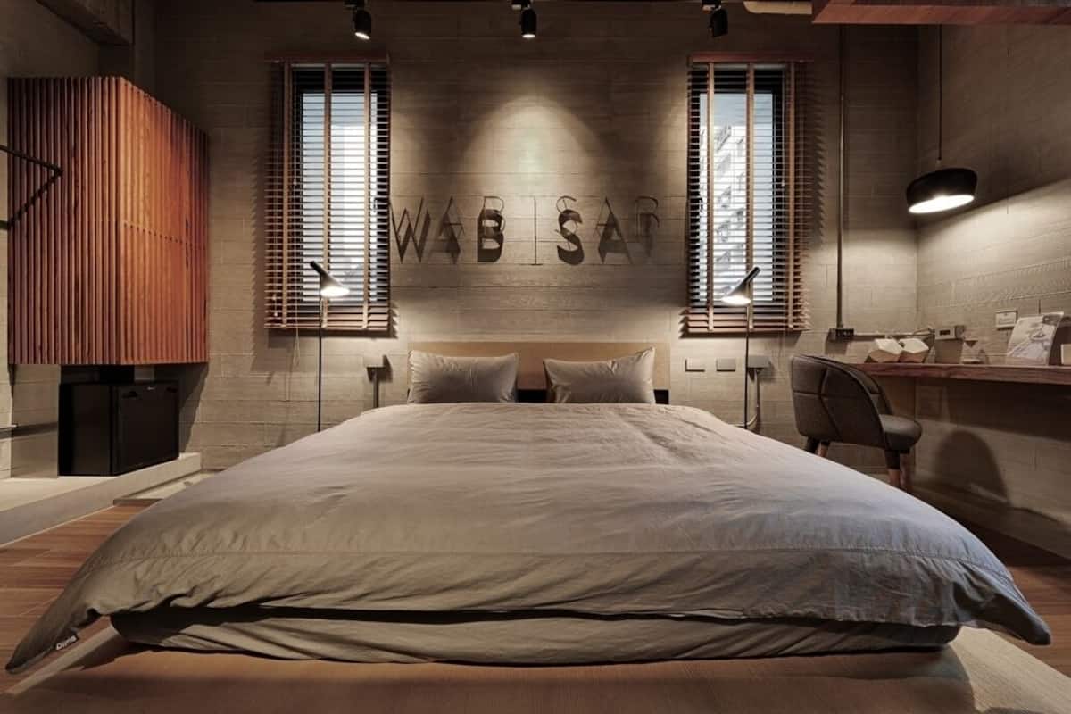 A modern bedroom with a large bed, a wooden slat wall, and a desk with a chair.