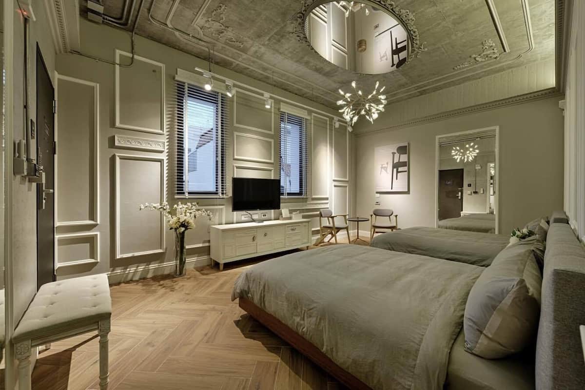 A bedroom with a large bed, a TV, a dresser, and a vanity.