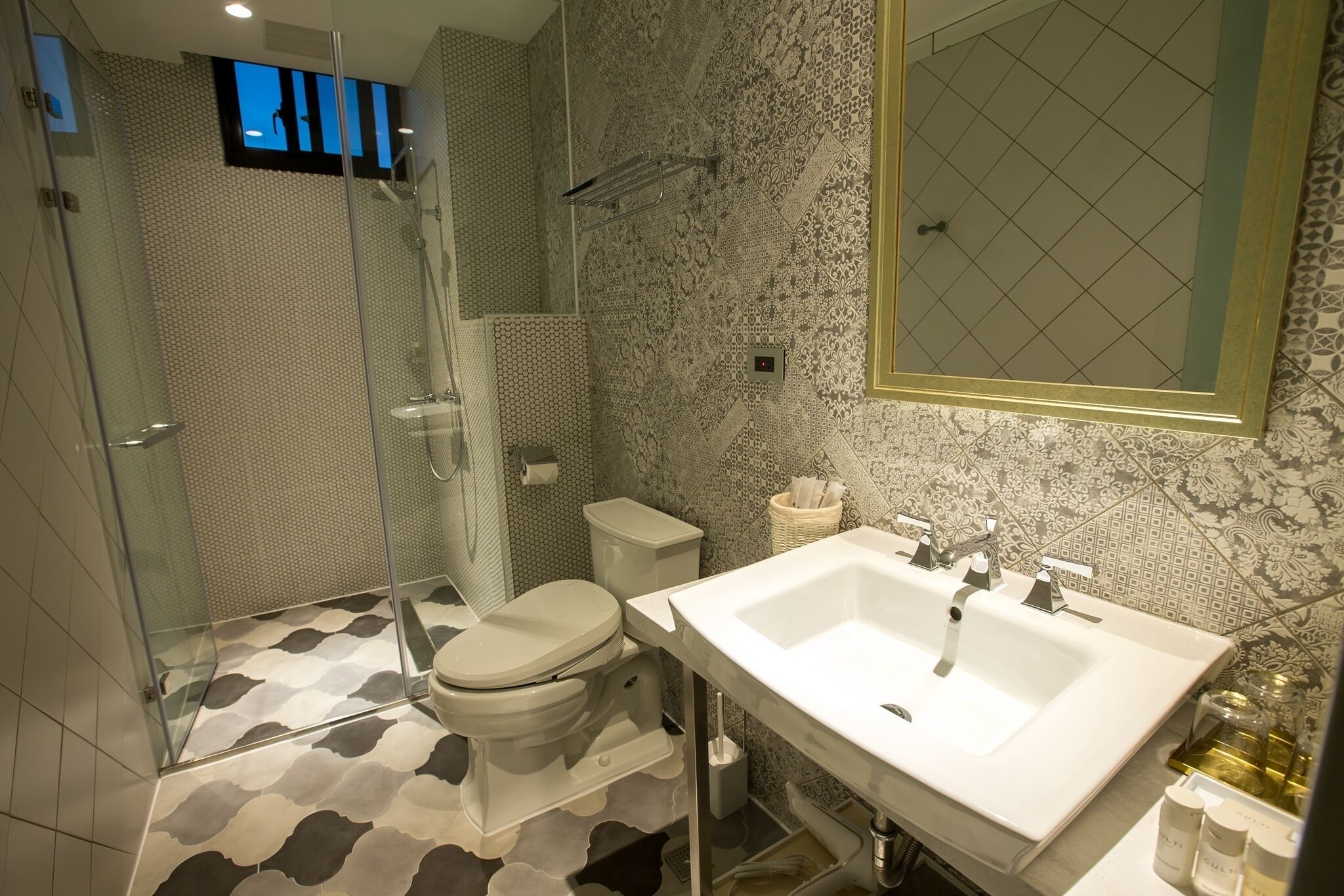 A modern bathroom with a glass shower enclosure, a toilet, and a large sink with a mirror.