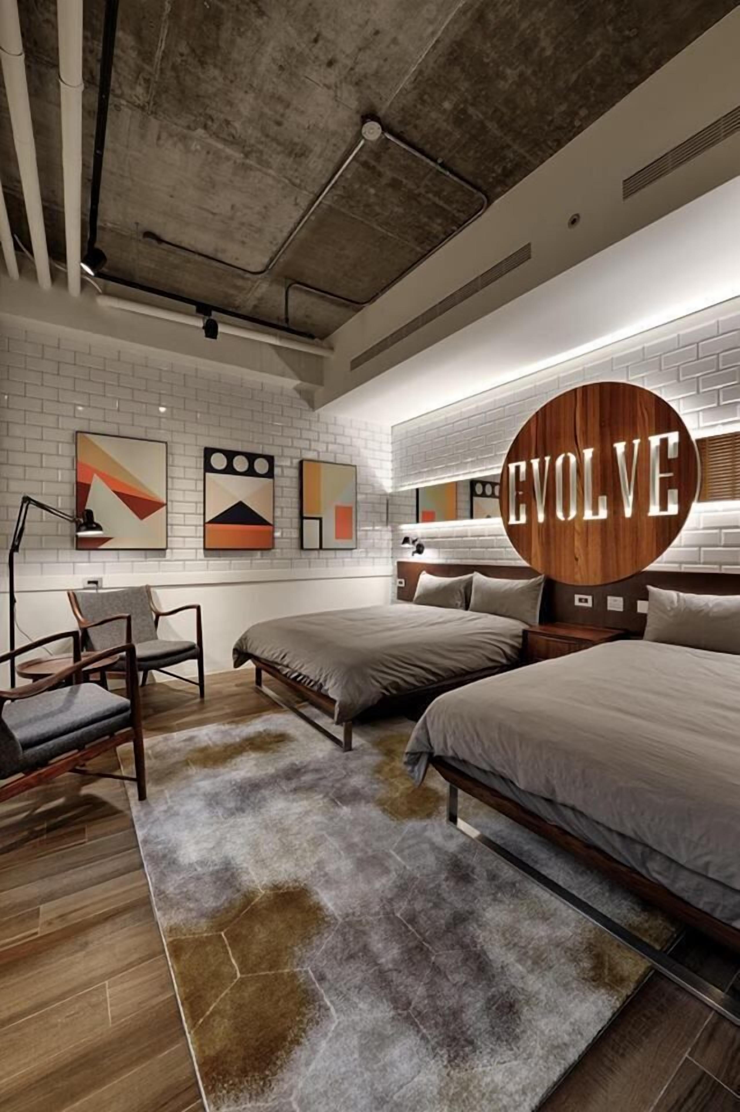 A modern bedroom with two beds, a desk, and a chair.