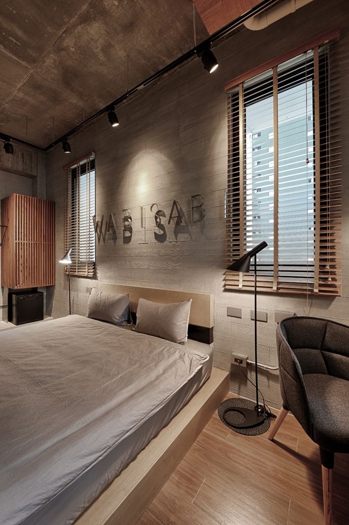 A modern bedroom with a large bed, wooden headboard, and a wall-mounted light fixture.