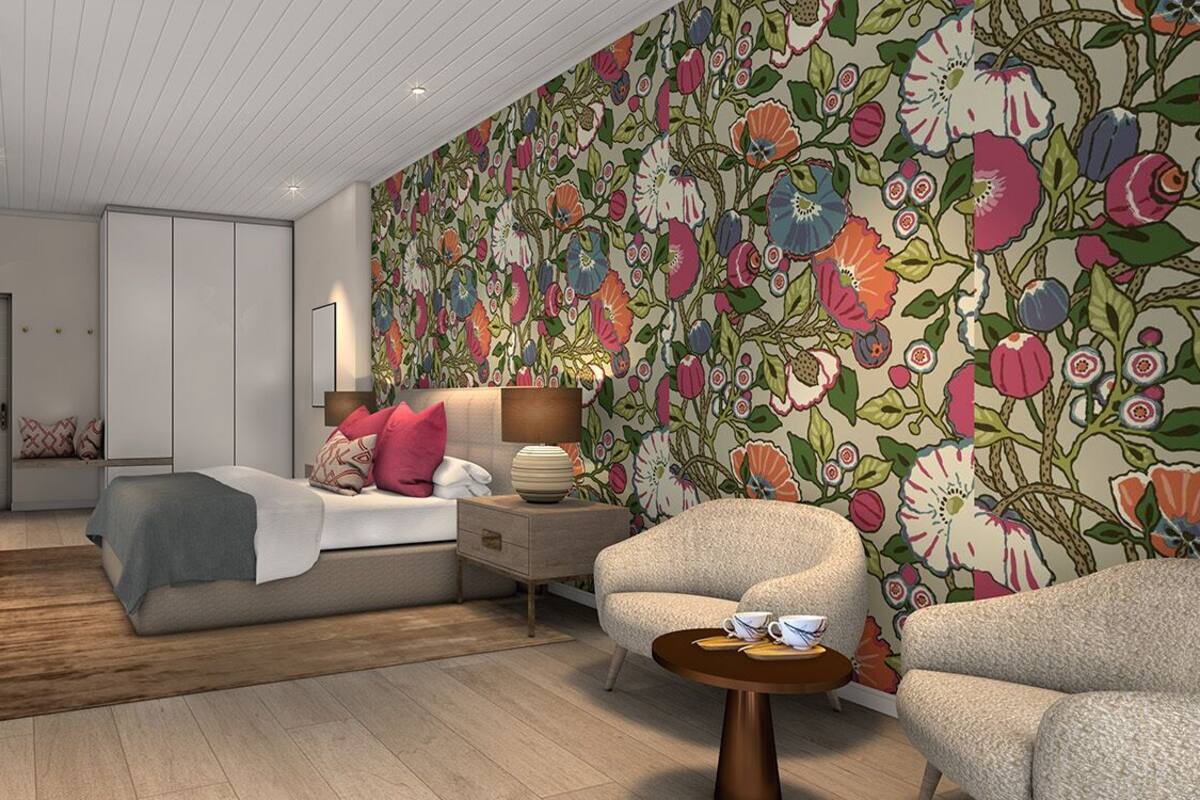 A modern bedroom with a bed, a nightstand, a chair, and a large floral wallpaper.