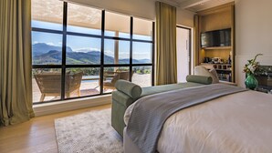 Quarto com uma janela grande, cama, área de estar e televisão.