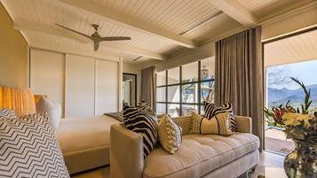 Una sala de estar moderna con un sofá, un ventilador de techo y un ventanal con vistas al exterior.
