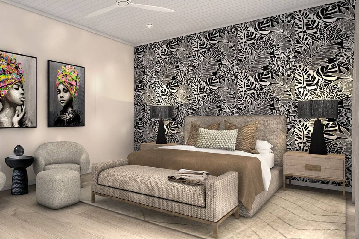A bedroom with a bed, two armchairs, a side table, and a patterned wallpaper.