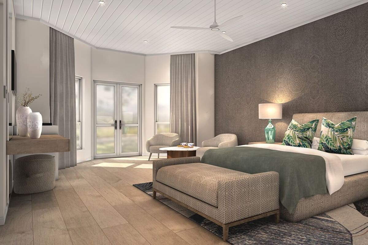 A modern bedroom with a large bed, two bedside tables with lamps, a sofa, and a view of the outdoors through a sliding door.