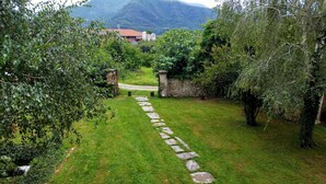 Un vialetto in pietra che si snoda attraverso un lussureggiante giardino, con una montagna sullo sfondo.