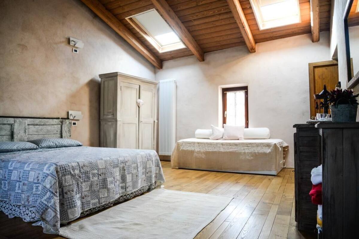 A bedroom with a wooden ceiling, a large bed, a wardrobe, and a radiator.