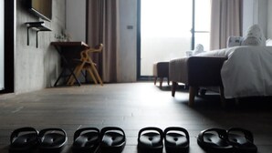 A hotel room with a bed, a desk, and a pair of slippers on the floor. - CoffeeLoft Inn &  Café (Taitung)