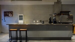 A modern kitchen with a large island, two stools, a coffee machine, and a refrigerator. - CoffeeLoft Inn &  Café (Taitung)