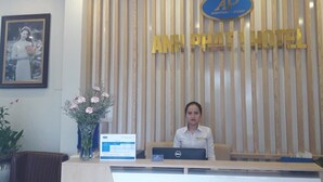 Een receptiebalie met een ingelijst foto, een laptop en een bord met de naam Anphathi Hotel.