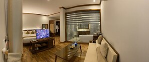 Une chambre d’hôtel équipée d’une télévision, d’un canapé, d’une table basse et d’une salle de bain avec baignoire et douche.