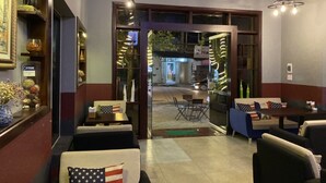 Een restaurantinterieur met zitjes, tafels en uitzicht op de straat.