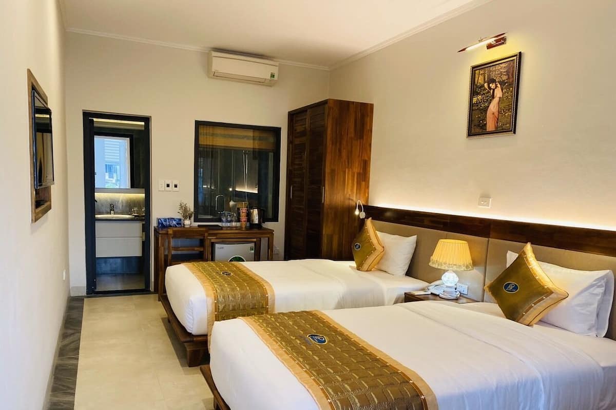 Een hotelkamer met twee bedden, een badkamer en een kleine kitchenette.