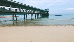 Uma praia com um píer que se estende para a água e a frase 'Good Morning' escrita na areia.
