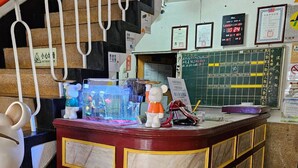 A reception desk with a marble design, a clock, and various signs and notices on the wall. - Huan Tai Hotel (Shuili)
