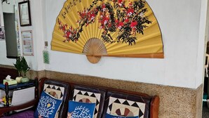 A room with a traditional fan painting on the wall, a wooden bed with patterned pillows, and a framed map above the bed. - Huan Tai Hotel (Shuili)