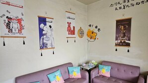 A room with two purple sofas, a white coffee table, and wall decorations including posters and a tiger illustration. - Huan Tai Hotel (Shuili)