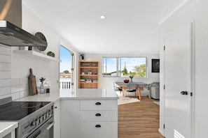 A modern kitchen with white cabinetry, a built-in oven, and a large window.