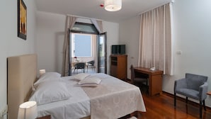 A bedroom with a bed, bedside lamps, a desk, a chair, a television, and a window with curtains. - Luxury Rooms near Beach (Split)
