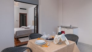 A hotel room with a bed, a dining table set with plates, glasses, and a bottle of wine. - Luxury Rooms near Beach (Split)