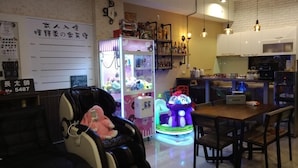A room with a massage chair, a claw machine, and a neon-lit toy. - Ching Yu Rou B&B (Dongshan)