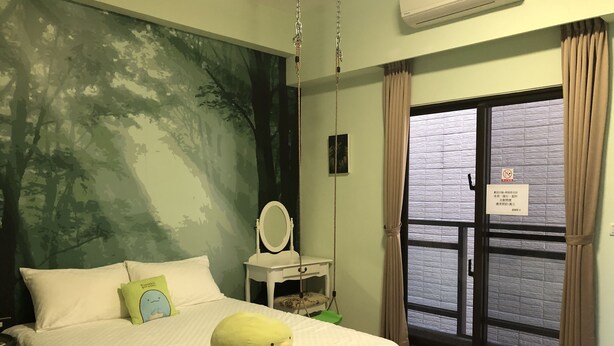 A bedroom with a bed, a hanging chair, a small table with a mirror, and a window with curtains. - Ching Yu Rou B&B (Dongshan)