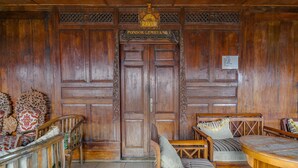 A traditional wooden room with a large wooden door, two wooden chairs, a small wooden table, and patterned floor tiles. - OYO 2157 Pondok Gembyang Air Panas Alam (Rancabali)