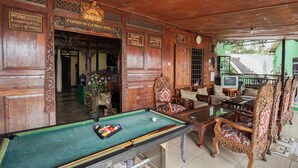 A wooden room with a pool table, ornate furniture, and a sign indicating 'Pondok Gemilang'. - OYO 2157 Pondok Gembyang Air Panas Alam (Rancabali)