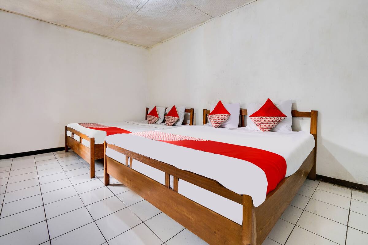 A room with a large bed, two smaller beds, white walls, and a tiled floor.