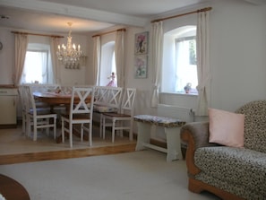 A dining area with a table and chairs, a chandelier, and a view of a garden through the window.